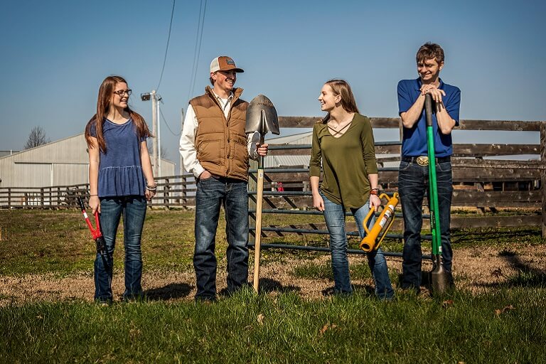 Four students posing with farming tools